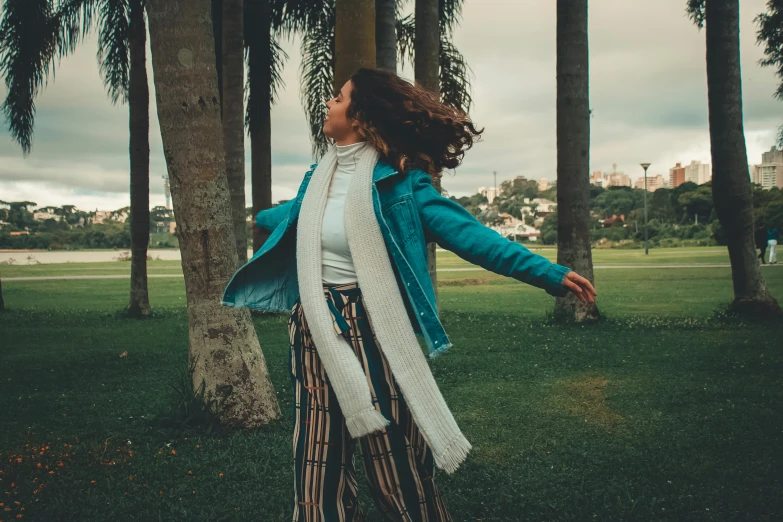 a woman standing on top of a lush green field, an album cover, inspired by Elsa Bleda, pexels contest winner, happening, palm trees in the background, wearing a jeans jackets, dancing elegantly over you, profile image