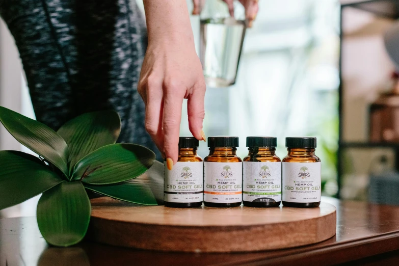 a close up of a person touching a bottle of essential oils, by Julia Pishtar, 4 cannabis pots, straya, various posed, official product photo