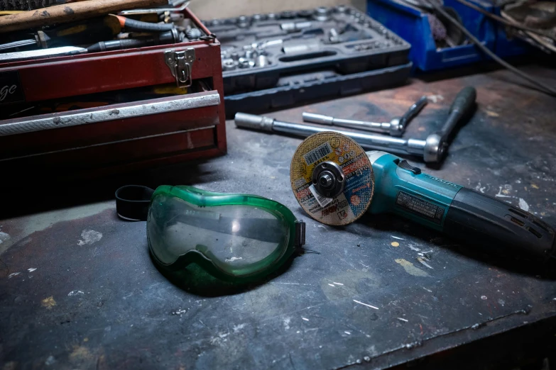 a couple of tools sitting on top of a table, a portrait, inspired by Jules Chéret, pexels contest winner, round goggles, in a workshop, aftermarket parts, green facemask