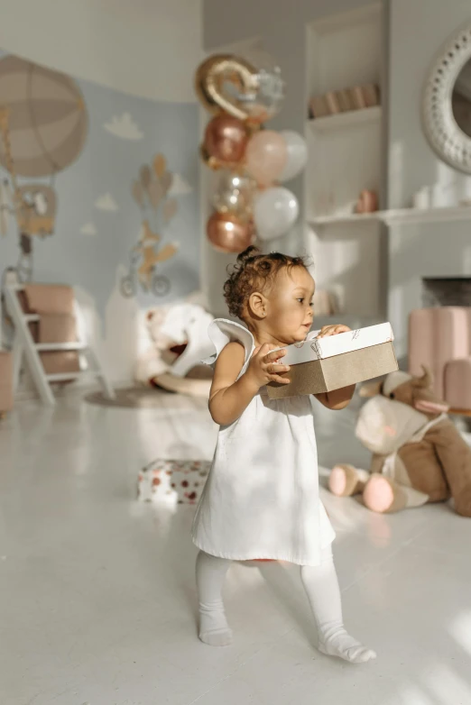 a little girl standing in a room holding a box, pexels contest winner, light and space, giving gifts to people, brown and white color scheme, toys, profile pic