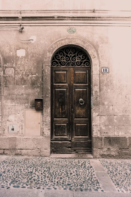 a couple of doors sitting on the side of a building, inspired by Taddeo Gaddi, pexels contest winner, renaissance, muted browns, arched doorway, quaint village, pareidolia