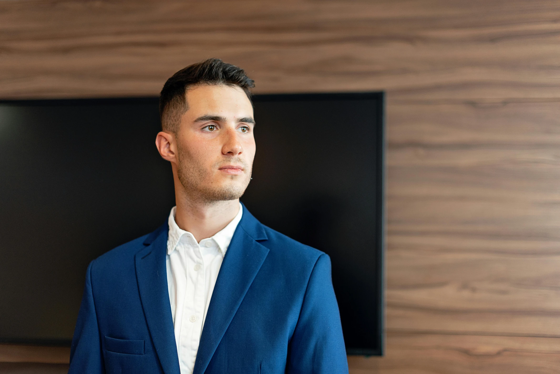 a man in a blue suit standing in front of a tv, by Niko Henrichon, pexels contest winner, f 1 driver charles leclerc, office clothes, professional profile picture, 21 years old