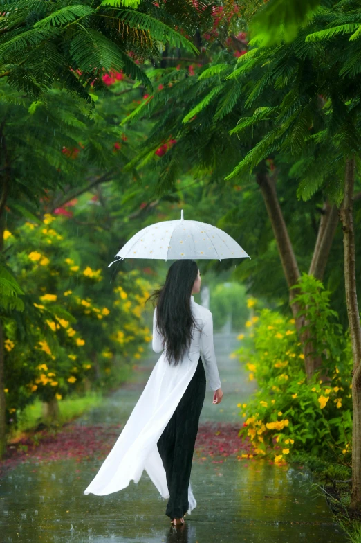 a woman walking in the rain with an umbrella, an album cover, inspired by Cui Bai, ao dai, botanical garden, white sleeves, grey