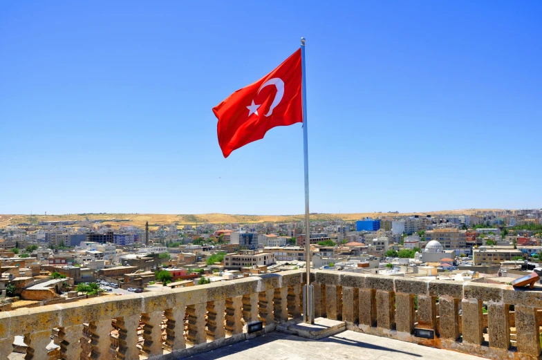 a turkish flag flying on top of a building, a colorized photo, pexels contest winner, hurufiyya, old town mardin, profile image, wide high angle view, square