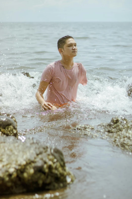 a man that is in the water with a frisbee, inspired by Ren Hang, unsplash, wearing seashell attire, wet shirt, non binary model, lush surroundings