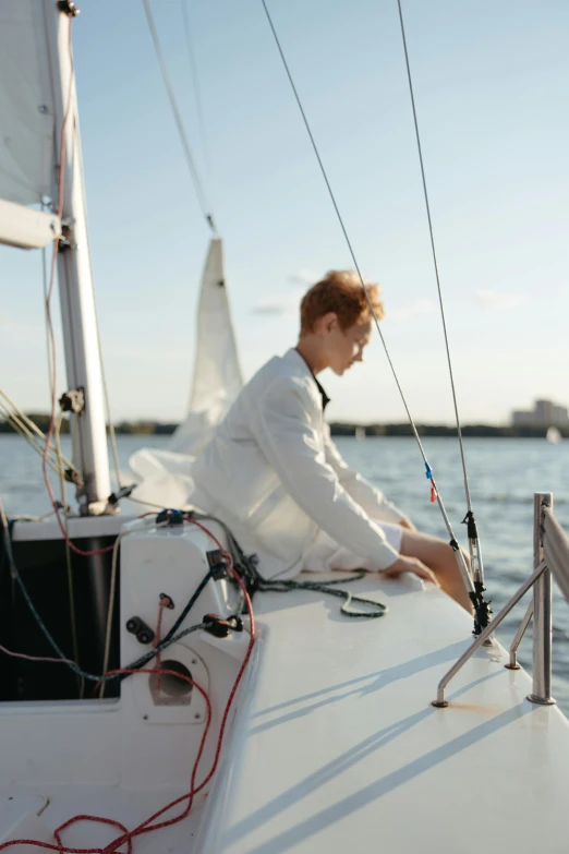 a man sitting on the bow of a sailboat, delicate androgynous prince, unsplash photo contest winner, ignant, sailor uniform