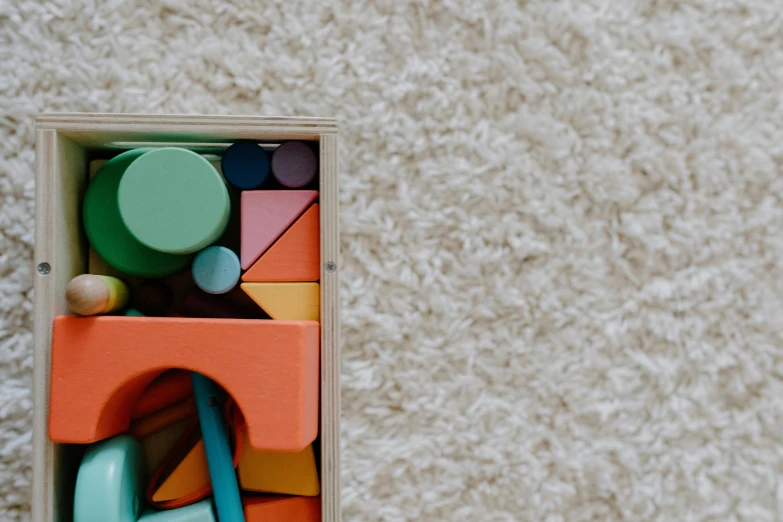 a close up of a toy in a wooden box, inspired by Frederick Hammersley, pexels contest winner, carpeted floor, solid coloured shapes, product image, rectangle