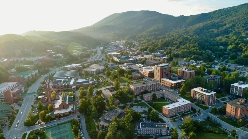 an aerial view of a campus with mountains in the background, by Carey Morris, unsplash contest winner, appalachian mountains, taken in the early 2020s, corduroy, buildings