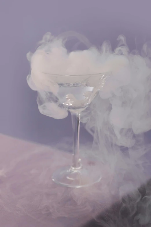 a glass filled with liquid sitting on top of a table, inspired by Carlo Martini, pexels contest winner, magic realism, cloud of smoke, in style of petra collins, white fluffy cloud, violet spike smoke