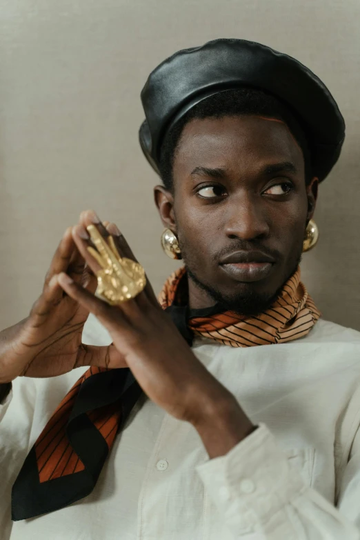 a close up of a person holding a piece of food, inspired by Barthélemy Menn, trending on pexels, afrofuturism, wearing gilded robes, handsome man, gold medal, dressed thobe