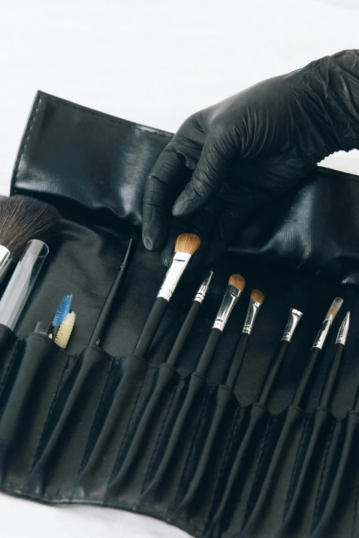 a close up of a person putting makeup brushes in a bag, dau-al-set, black leather gloves, black robes, thumbnail, premium