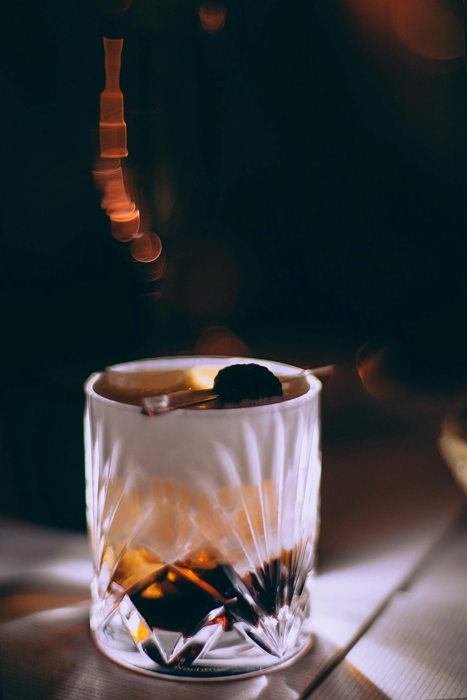 a glass filled with liquid sitting on top of a table, a portrait, inspired by Carlo Martini, unsplash, cozy dark 1920s speakeasy bar, profile image, maple syrup & hot fudge, medium format. soft light