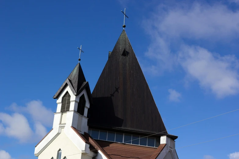 a white church with a black steeple against a blue sky, an album cover, unsplash, hurufiyya, reykjavik junior college, peaked wooden roofs, 15081959 21121991 01012000 4k, decoration