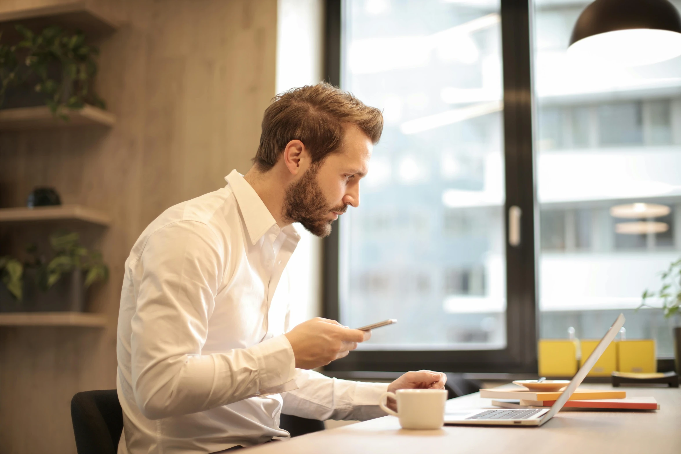 a man sitting at a table in front of a laptop, pexels contest winner, profile image, australian, looking at his phone, people at work