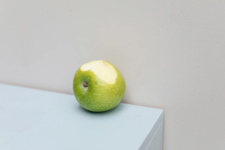 a green apple sitting on top of a blue table, inspired by Euan Uglow, light green, small nose, wall corner, product shot