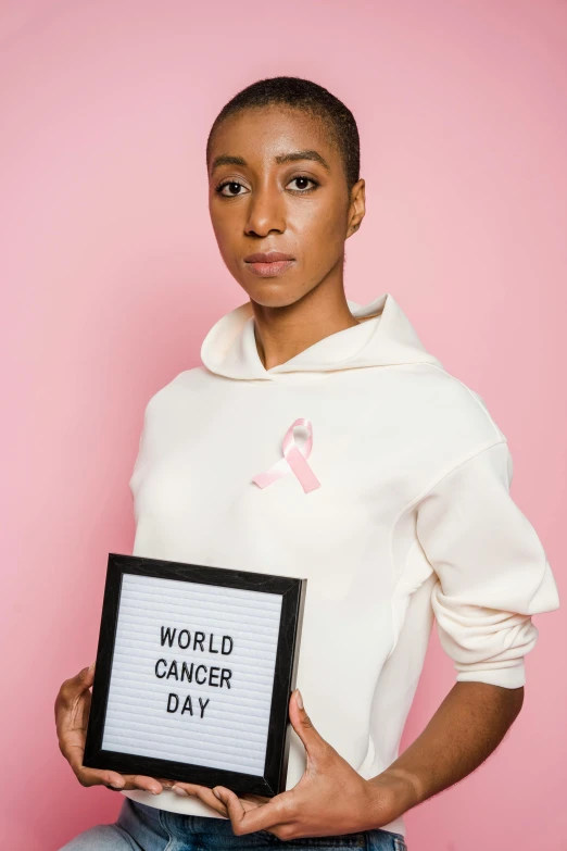 a woman holding a sign that says world cancer day, a photo, by Arabella Rankin, ashteroth, pr shoot, promo image, white ribbon