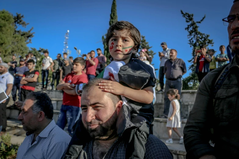 a young boy sitting on top of a man's head, by Ibrahim Kodra, pexels contest winner, hurufiyya, damascus, patriotism, over his shoulder, square