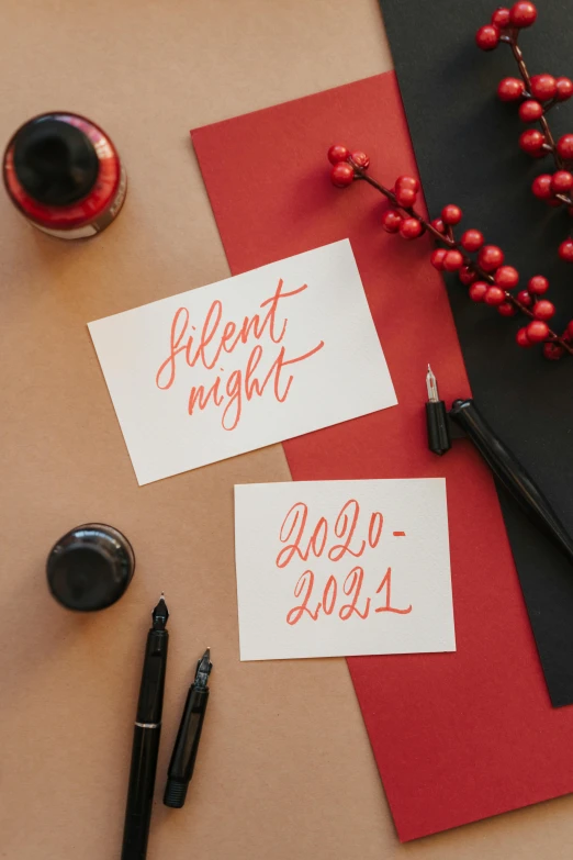 a couple of cards sitting on top of a table, by Julia Pishtar, trending on pexels, calligraphy, festive colors, almost night, brush pen