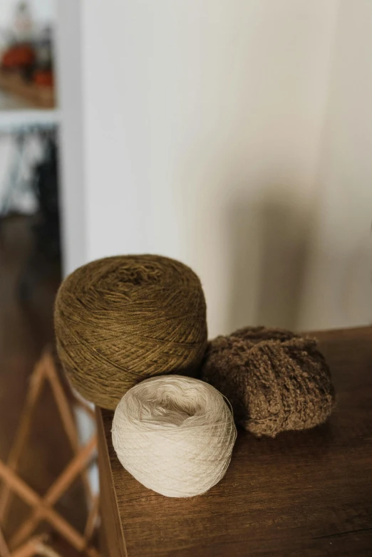 a pile of yarn sitting on top of a wooden table, by Jessie Algie, renaissance, brown and white color scheme, spheres, ignant, indoor shot
