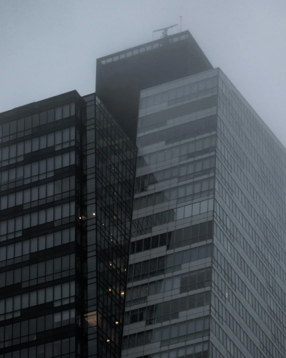 a couple of tall buildings sitting next to each other, an album cover, inspired by David Chipperfield, pexels contest winner, moist foggy, office building, chilly dark mood, no cropping