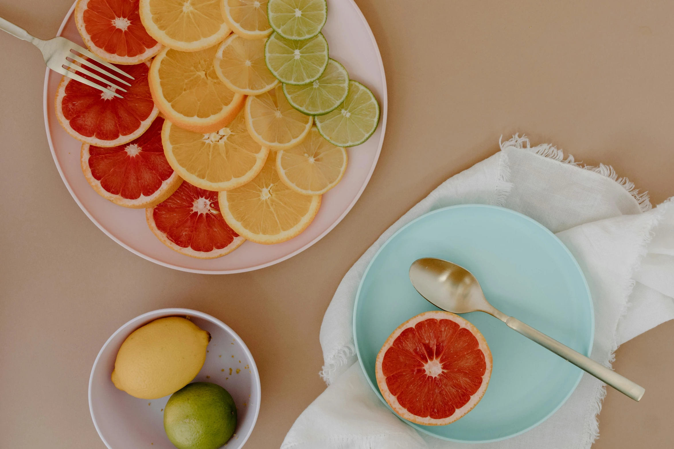 a close up of a plate of fruit on a table, by Carey Morris, trending on pexels, pink and teal and orange, sliced grapefruit, ingredients on the table, plain background