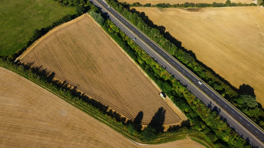 an aerial view of a highway surrounded by fields, by Julian Allen, unsplash, land art, slight stubble, ground angle uhd 8 k, robert maplethorpe, 2000s photo