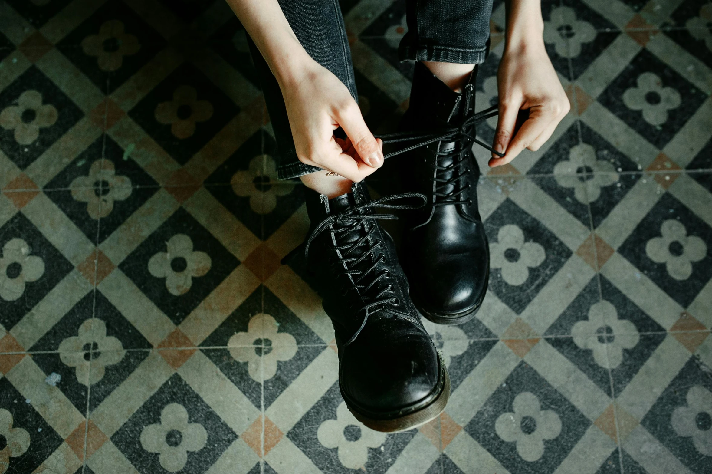 a person tying up a pair of black shoes, inspired by Elsa Bleda, trending on pexels, antipodeans, doc marten boots, with pale skin, at home, girl wearing uniform