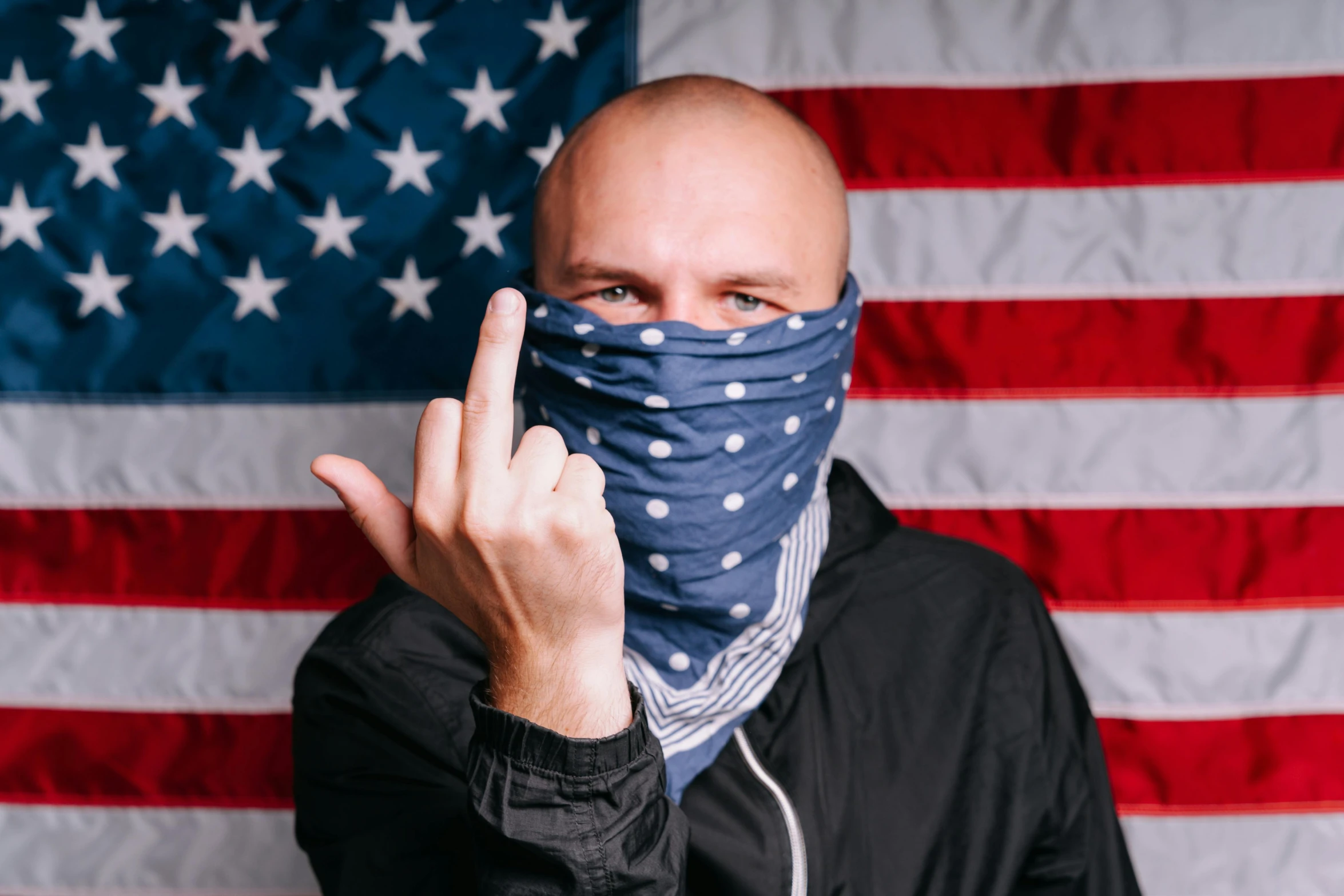 a man wearing a bandana in front of an american flag, inspired by Brian 'Chippy' Dugan, unsplash, graffiti, middle finger, a bald, surgical mask covering mouth, menacing pose