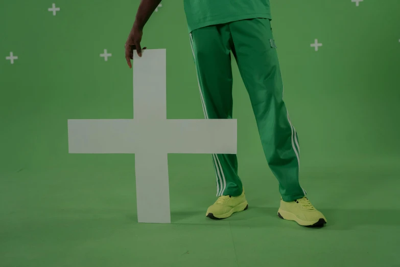 a man standing next to a cross on a green screen, trending on pexels, video art, wearing adidas clothing, green legs, medicine, formulas