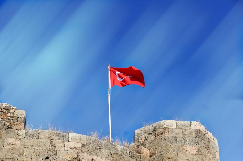 a red flag flying on top of a stone wall, pexels contest winner, hurufiyya, turkey, square, sky blue, silver