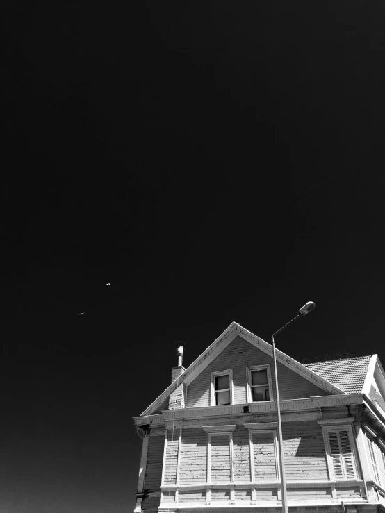 a black and white photo of a large house, a black and white photo, by Christopher Williams, postminimalism, ufo in the sky, san francisco, planets in the skies, medium format. soft light