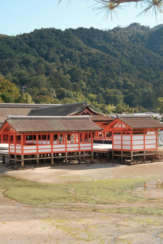 a red and white building next to a body of water, sōsaku hanga, gazebos, japan mountains, zoomed out view, square