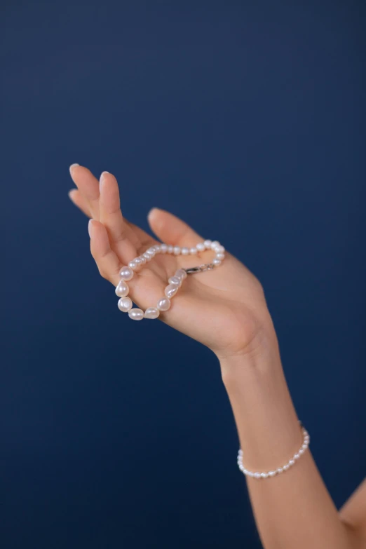a woman holding a pearl necklace in her hand, photo of a hand jewellery model, left align content, product shoot, multiple stories