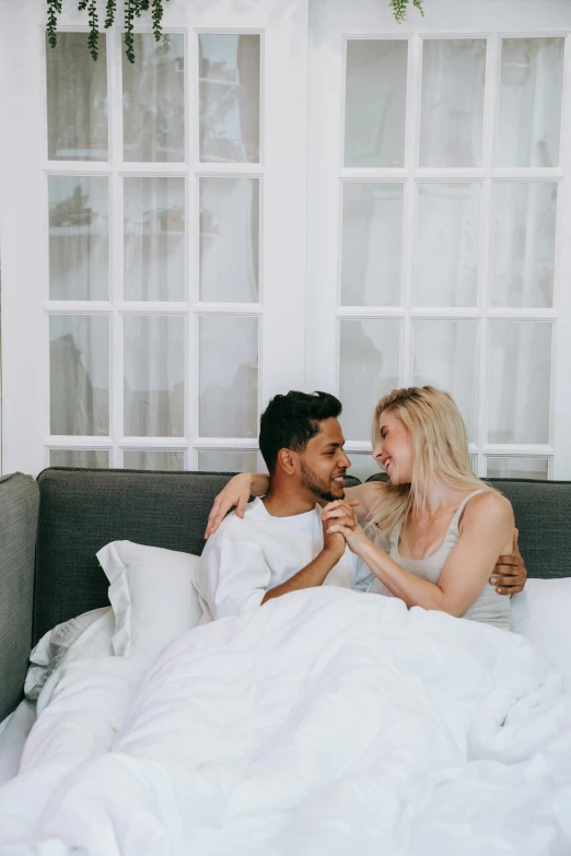 a man and woman laying in bed next to each other, pexels contest winner, flirty, blonde guy, full profile, in white room