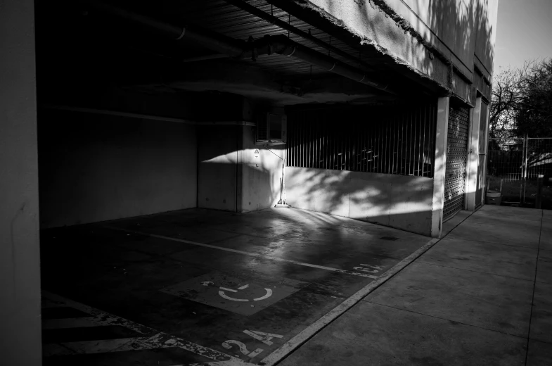 a black and white photo of a parking garage, unsplash, light and space, deep shadows and colors, shady alleys, some sun light ray, low iso