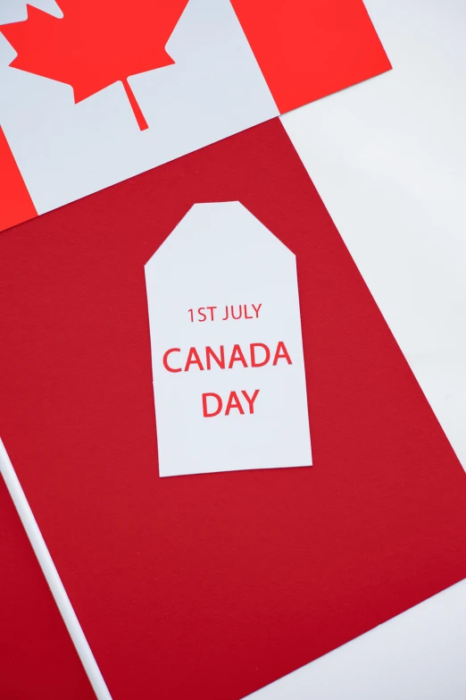 a canadian flag with a tag that says canada day, by Julia Pishtar, international typographic style, printed page, detail shot, detailed product shot, 3 - piece