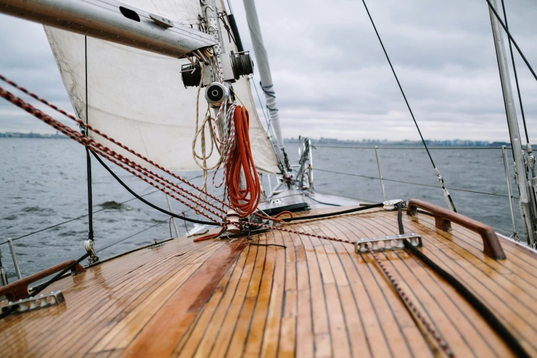 a close up of a boat on a body of water, pexels contest winner, on the deck of a sailing ship, grey skies, a wooden, lachlan bailey