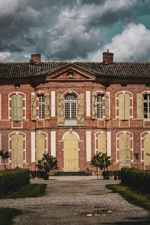 a large brick building sitting on top of a lush green field, inspired by François Barraud, pexels contest winner, renaissance, yellow windows and details, slate, square, aristocratic