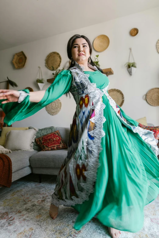 a woman in a green dress dancing in a living room, inspired by Li Di, reddit, arabesque, mongolia, wearing authentic attire, new mexico, mai anh tran