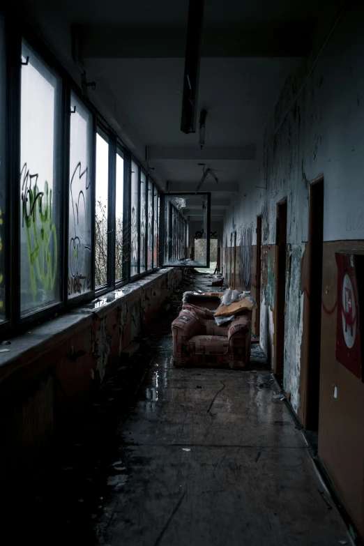 a long hallway in an abandoned building with lots of windows, inspired by Elsa Bleda, graffiti, couches melting, dark eerie photograph, windows and walls :5, high school