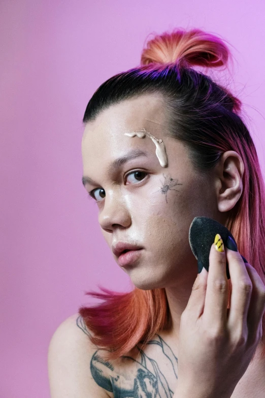 a woman with pink hair brushes her face with a brush, an album cover, trending on pexels, bauhaus, portrait sophie mudd, androgynous male, markings on his face, asian features