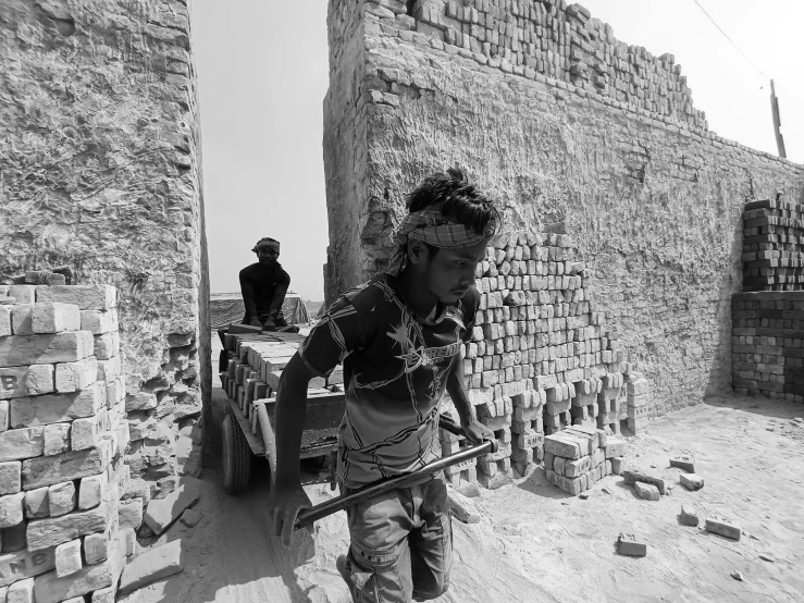 a black and white photo of a man carrying bricks, by Sudip Roy, pexels contest winner, fortress mega structure city, android girl in egyptian ruins, working hard, face