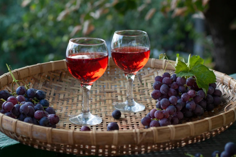 two glasses of wine and grapes on a wicker tray, pexels contest winner, indigo and venetian red, al fresco, red hues, auslese