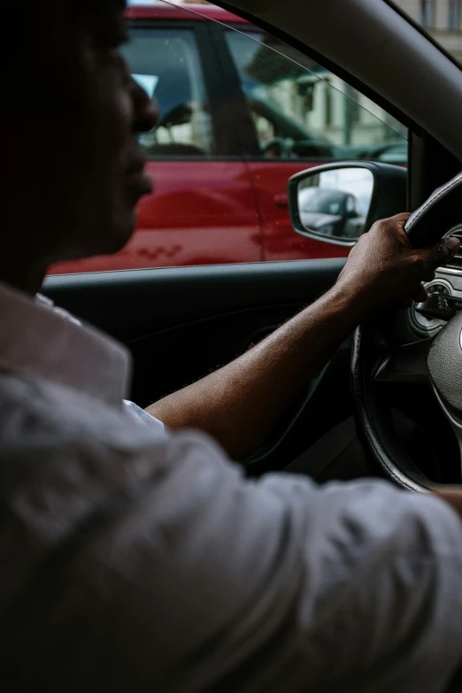 a man driving a car on a city street, by Matt Stewart, trending on unsplash, square, dynamic closeup, photographed for reuters, dark-skinned