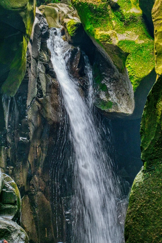 a man standing in front of a waterfall, sumatraism, photograph from above, overgrown stone cave, haida, award winning color photo