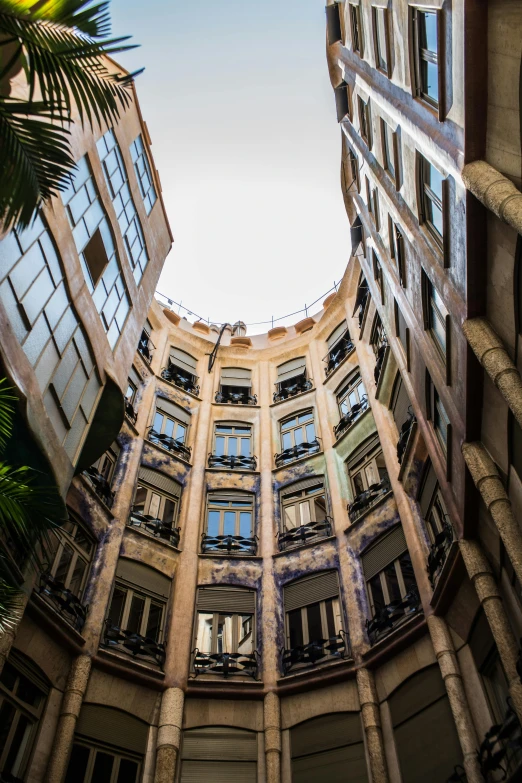 a very tall building with lots of windows, by Gaudi, unsplash, alleys, rounded ceiling, crenellated balconies, looking down