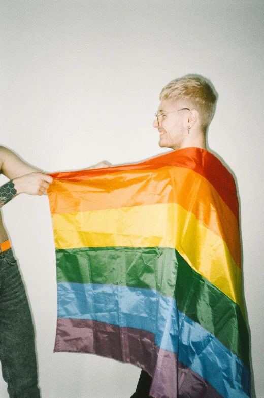 a man and a woman holding a rainbow flag, an album cover, by Jessie Alexandra Dick, trending on pexels, blond boy, gang flags, high quality photo, cai xukun