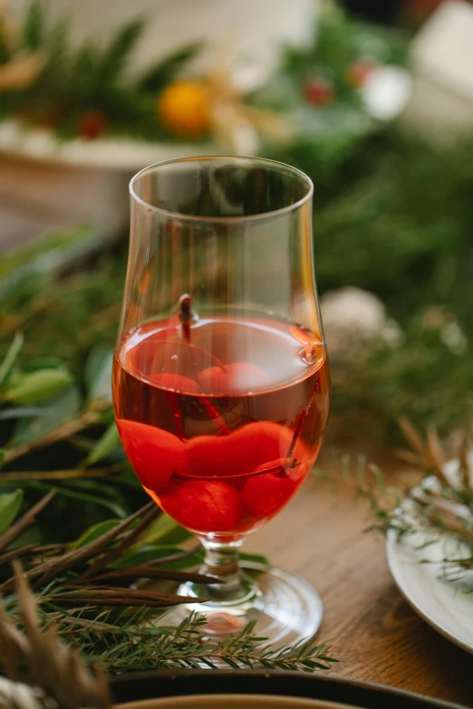 a glass of wine sitting on top of a table, botanicals, winter setting, cherry, featured