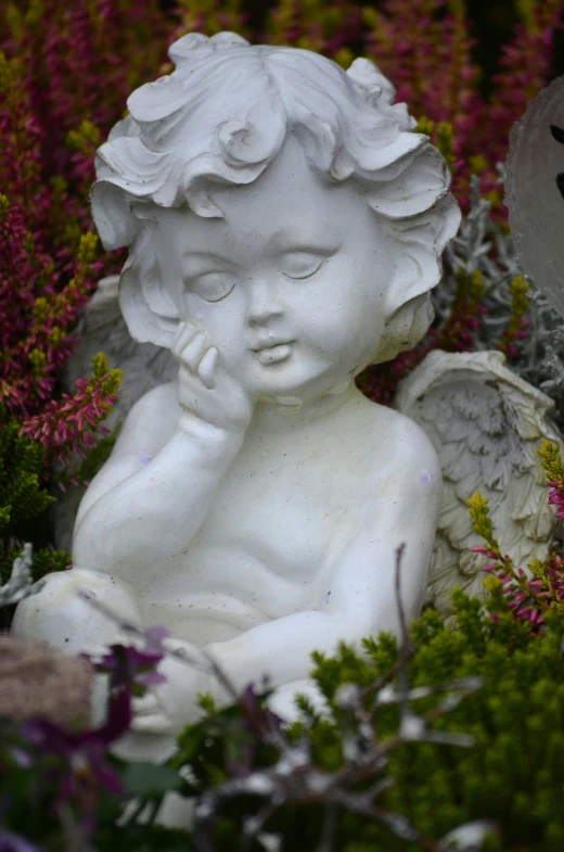 a statue of an angel sitting in a garden, with soft bushes, smirking, precious moments, trending photo