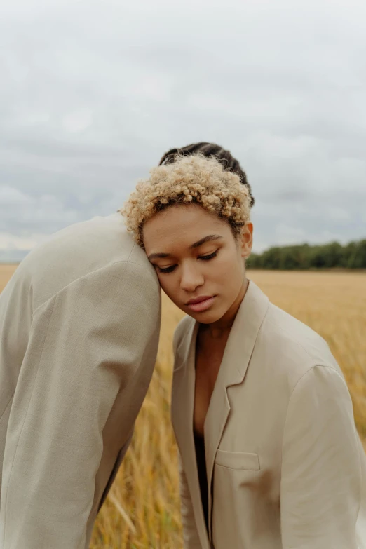 a woman standing in the middle of a wheat field, trending on pexels, renaissance, two men hugging, short blonde afro, imaan hammam, pale beige sky